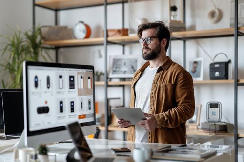 Muž stojící v kanceláři s tabletem v ruce.